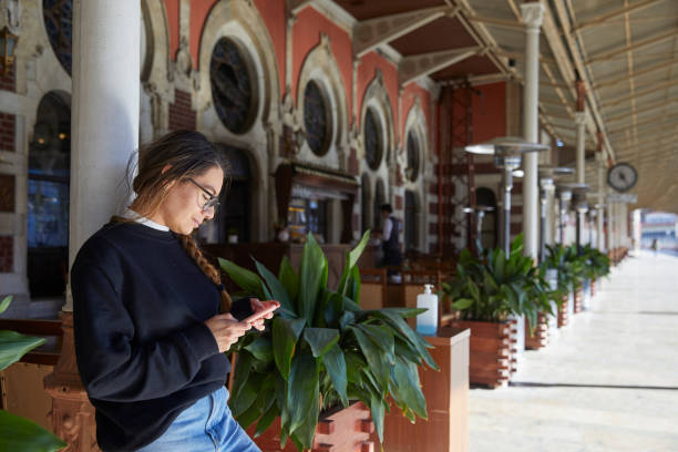 istock tourist lady leaning to column and messaging with mobile phone 1567351472