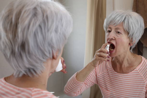 istock Senior woman using a mouth spray 1567356022