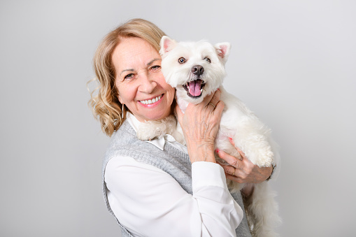 A Cheerful retired senior woman with dog and enjoying time with pet on studio white