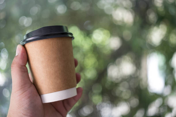 istock Men holding takeaway paper coffee cup on light nature background. 1567362807