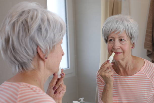 istock Senior woman moisturizing her lips in the bathroom 1567367866