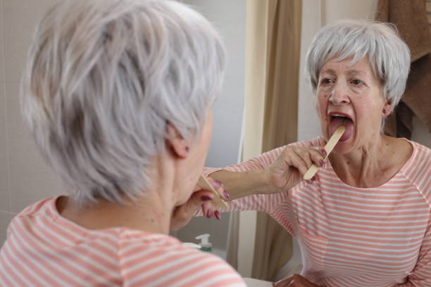 starsza kobieta badająca własne gardło - healthcare and medicine pain candid senior adult zdjęcia i obrazy z banku zdjęć