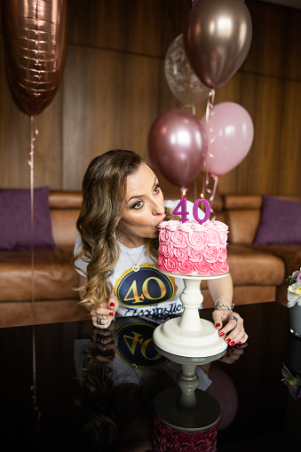 One woman, mature woman kissing her 40th birthday cake.