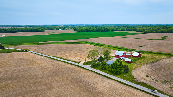 Image of Estate property asset red barn, farmhouse, shed empty, tilled fields and green pasture with forest