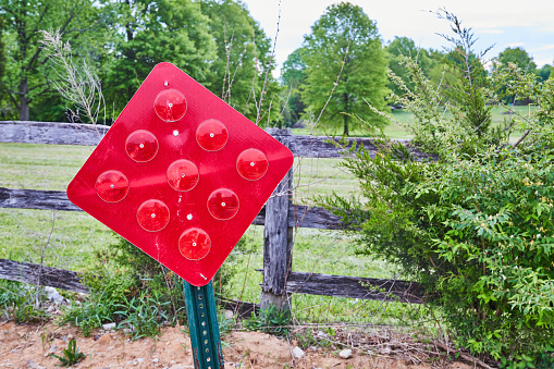 Image of Falling over red closed roadway sign in rural area with decaying fence in summer