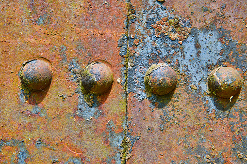 Image of Four rivets split by crack on rusty decaying corroding iron metal industrial background asset