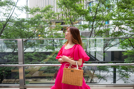 Woman in pink dress standing in city
