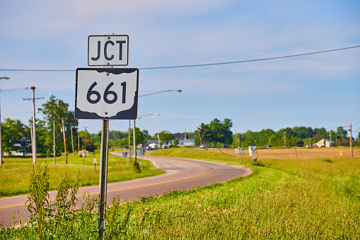Image of JCT 661 sign next to highway in summer with blue sky and thin clouds