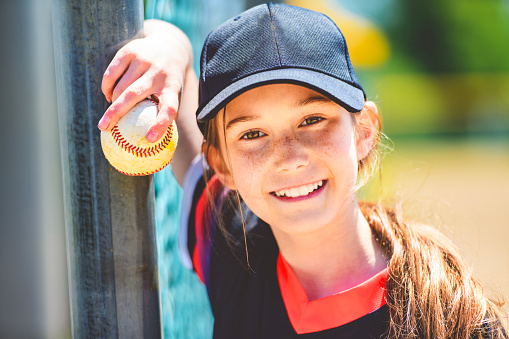 A Young girl play baseball on summer day