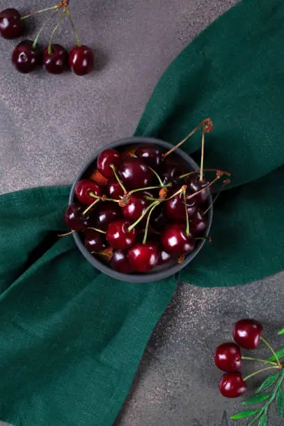 Photo of Black cherries on a gray plate on green cloth