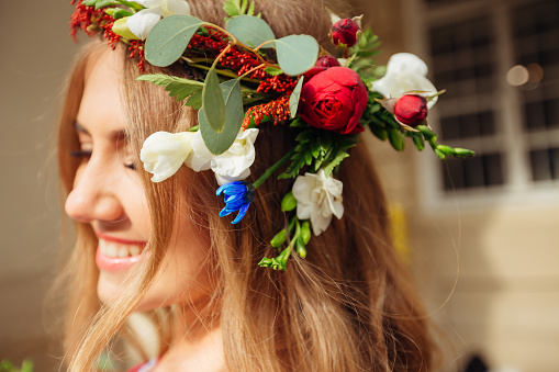 Creative crown of fresh flowers on a head of beautiful blond girl