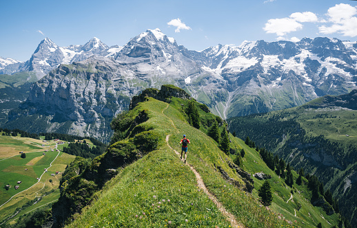 Trail runner ascends alpine path in Swiss mountain landscape