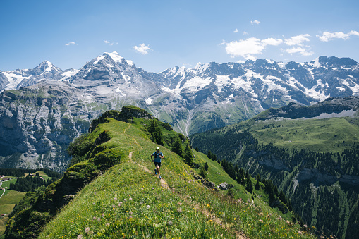 istock Trail runner ascends alpine path in Swiss mountain landscape 1567426296