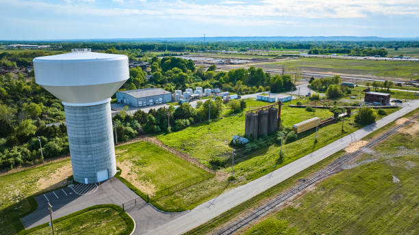 istock Nondescript white water tower in farmland green fields, train tracks, abandoned silo rural 1567441225