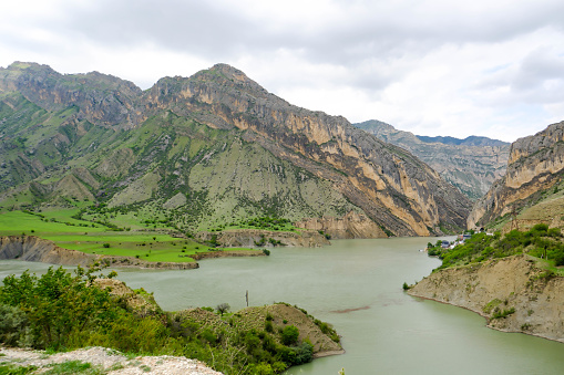 The landscape of the Caucasus Mountains river on the background of a blue sky with clouds.