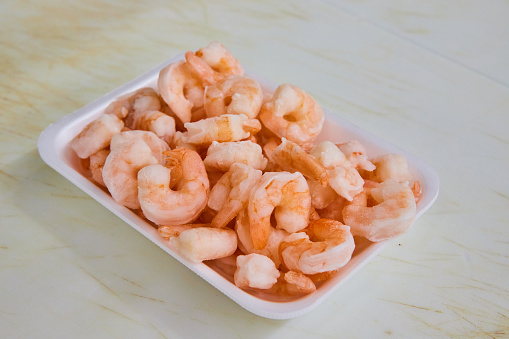 Image of Pile pink cooked shrimp, seafood on white tray, grocery store, meat department