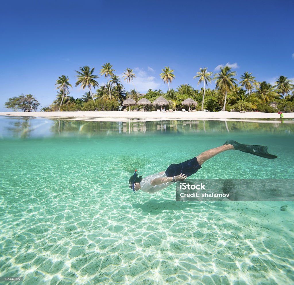 Man swimming underwater Man swimming in a tropical lagoon in front of exotic island Maldives Stock Photo