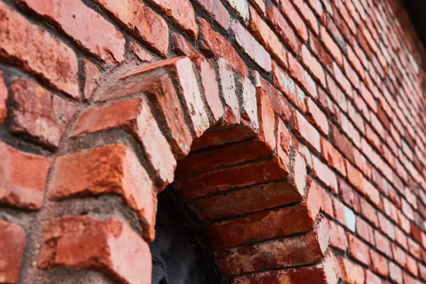 istock Slanted red brick wall with protruding circular archway on bottom and black motif inside circle 1567468514