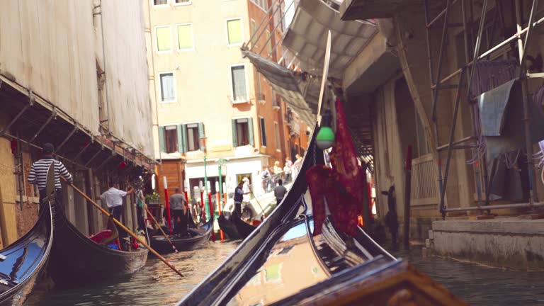 Gondolas with tourists waiting for disembarkation at the end of the tour through the canals of Venice, Italy.