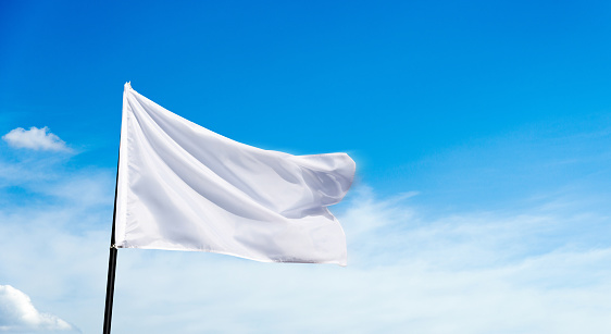 White flag flying against blue sky background