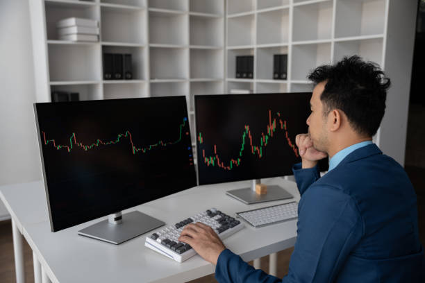 istock Young businessman holding hands on his face while sitting at the desk in creative office, stock market concept. 1567483250