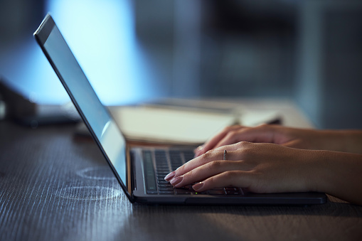 Woman, hands and laptop at night typing email for communication, social media or browsing. Closeup of female person or employee working late on computer for online chatting, networking or texting