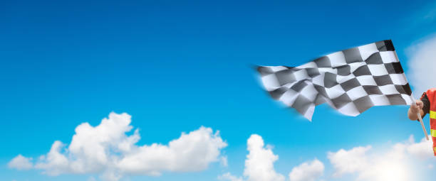 istock Checkered race flag in hand against blue sky 1567486526