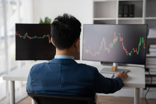 istock Young businessman holding hands on his face while sitting at the desk in creative office, stock market concept. 1567486641