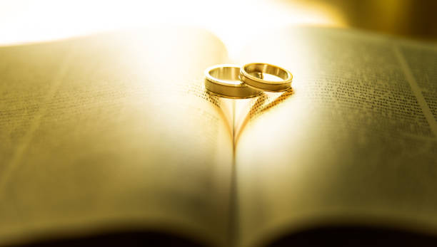 Two wedding rings with heart shadow  on a bible page stock photo