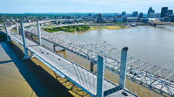Image of White suspension and truss bridges over dirty water of Ohio River aerial Louisville skyline