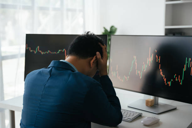 istock Young businessman holding hands on his face while sitting at the desk in creative office, stock market concept. 1567503929