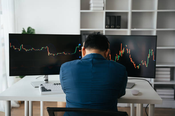 istock Young businessman holding hands on his face while sitting at the desk in creative office, stock market concept. 1567505705