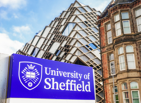 Sheffield, UK - Close up of a sign for the University of Sheffield, with The Diamond building, used by the university's engineering department, in the background.