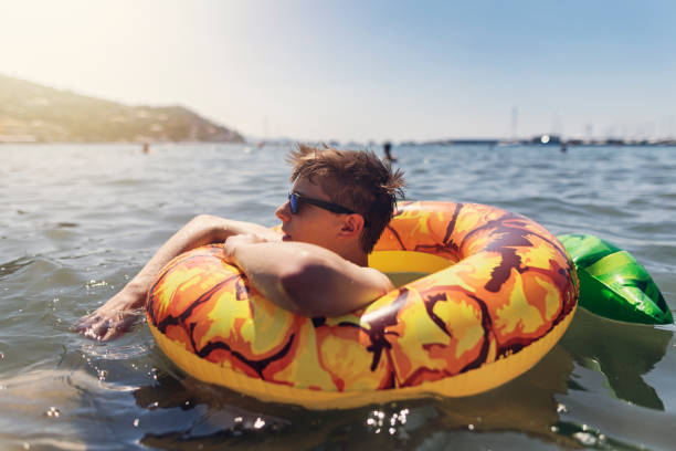 istock Teenage boy enjoying summer vacations in one inflatable float ring 1567522132
