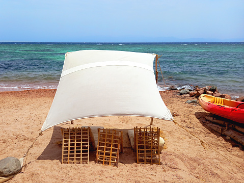 Rustic Berber chill out on the Red Sea coast in the Sinai Peninsula. Rustic canvas on the beach of Dahab. Awning and tent in the desert. Desert decoration.