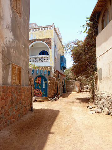 View of facades on sandy street of Dahab in the Sinai desert. Traditional houses of Egyptian seaside town. Arab culture and Red Sea. Architecture and construction.