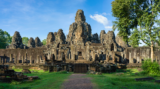 Spotlit Bayon Temple, a Khmer temple related to Buddhism at Angkor Wat Park in Cambodia under blue sunny summer sky. 102 MPixel Hasselblad X2D Ancient Architecture Panorama 16:9 Crop. Bayon (Banyan) Khmer Temple Angkor Thom City close to Angkor Wat Archaeological Area, Siem Reap, Cambodia, Southeast Asia, Asia.
