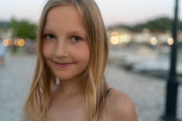 Art portrait of a beautiful girl. Street and people on blurred background with bokeh effect. Beautiful smiling teenage girl in blue blouse, against green of summer park.