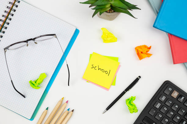 istock Notebook, glasses and paper reminders with the word school on a white background. 1567541556
