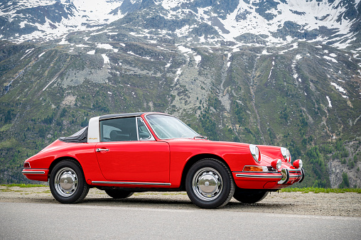 Porsche 912 Targa classic sports car parked alongside and alpine roadd high up in the Tyroler Alps in Austria. The Porsche 912 Targa is a classic sports car produced by Porsche AG from 1965 to 1969. The Targa variant of the 912 was introduced in 1966 and was known for its distinctive open-top design with a rollbar and removable top and rear section of the roof.