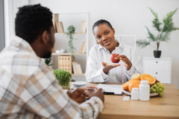istock Nutritionist holding apple with measuring tape at doctor's 1567548911