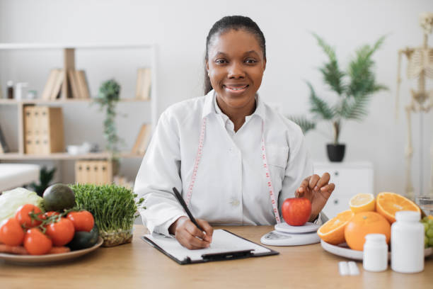 istock Professional assessing apple on scales in consulting room 1567550434