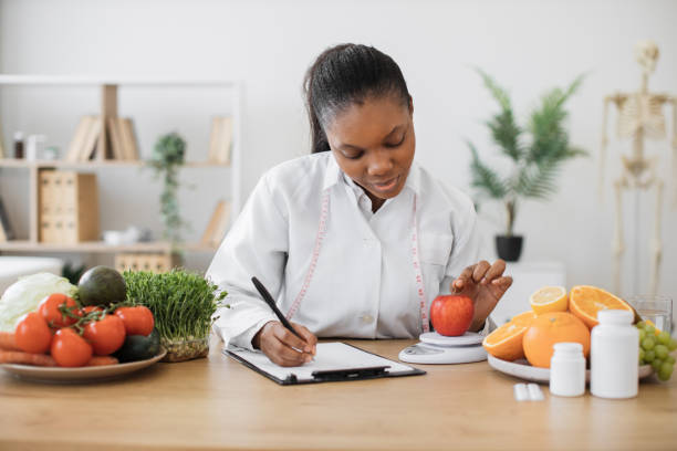 istock Professional assessing apple on scales in consulting room 1567550459