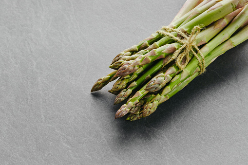 Asparagus on dark background, top view. Copy space. Fresh healthy vegetable