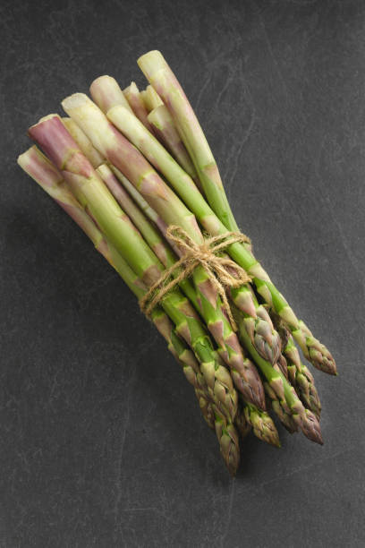 istock Asparagus on dark background, top view. 1567563663