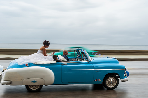 HAVANA, CUBA - OCTOBER 21, 2017: Old Car in Havana, Cuba. Retro Vehicle Usually Using As A Taxi For Local People and Tourist. Caribbean Sea in Background. Panning Blue Color Car