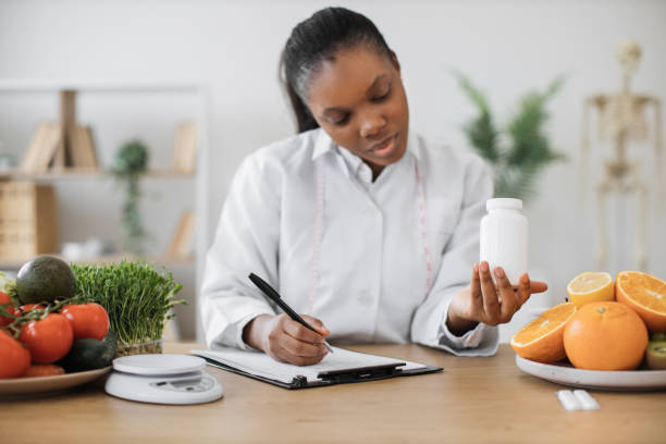 istock Female with medicine bottle writing on paper in office 1567589430