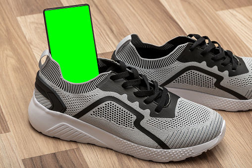 Green screen smartphone inside a sports shoe copy space.