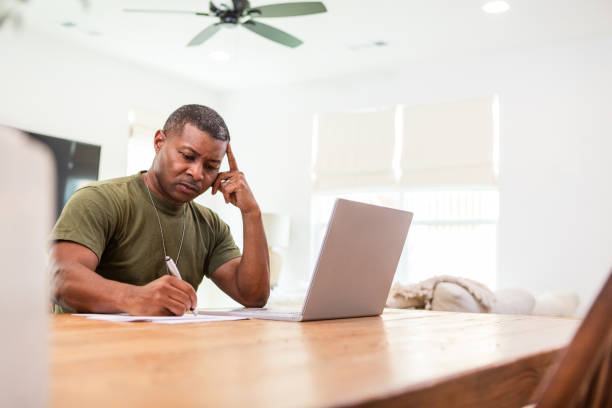 istock Male soldier sits at his dining room table to work on the computer during his lunch break 1567644521