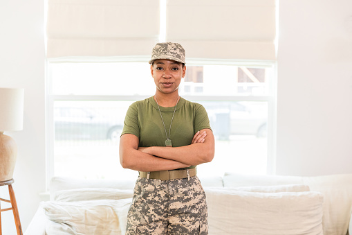 The proud female military service member stands with her arms crossed to have her photo taken.